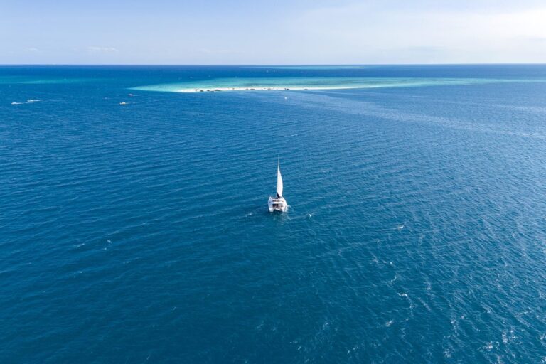 Catamaran sailing through turquoise water towards a sandbank in Zanzibar