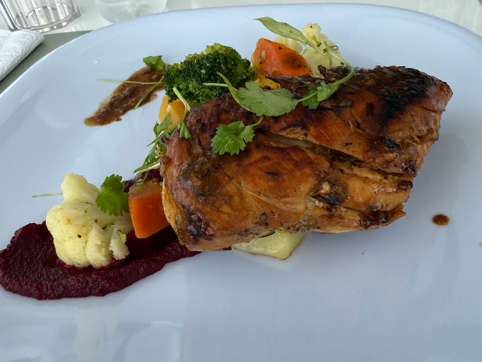 Plated grilled main course with vegetables and beetroot purée prepared by our chef on board