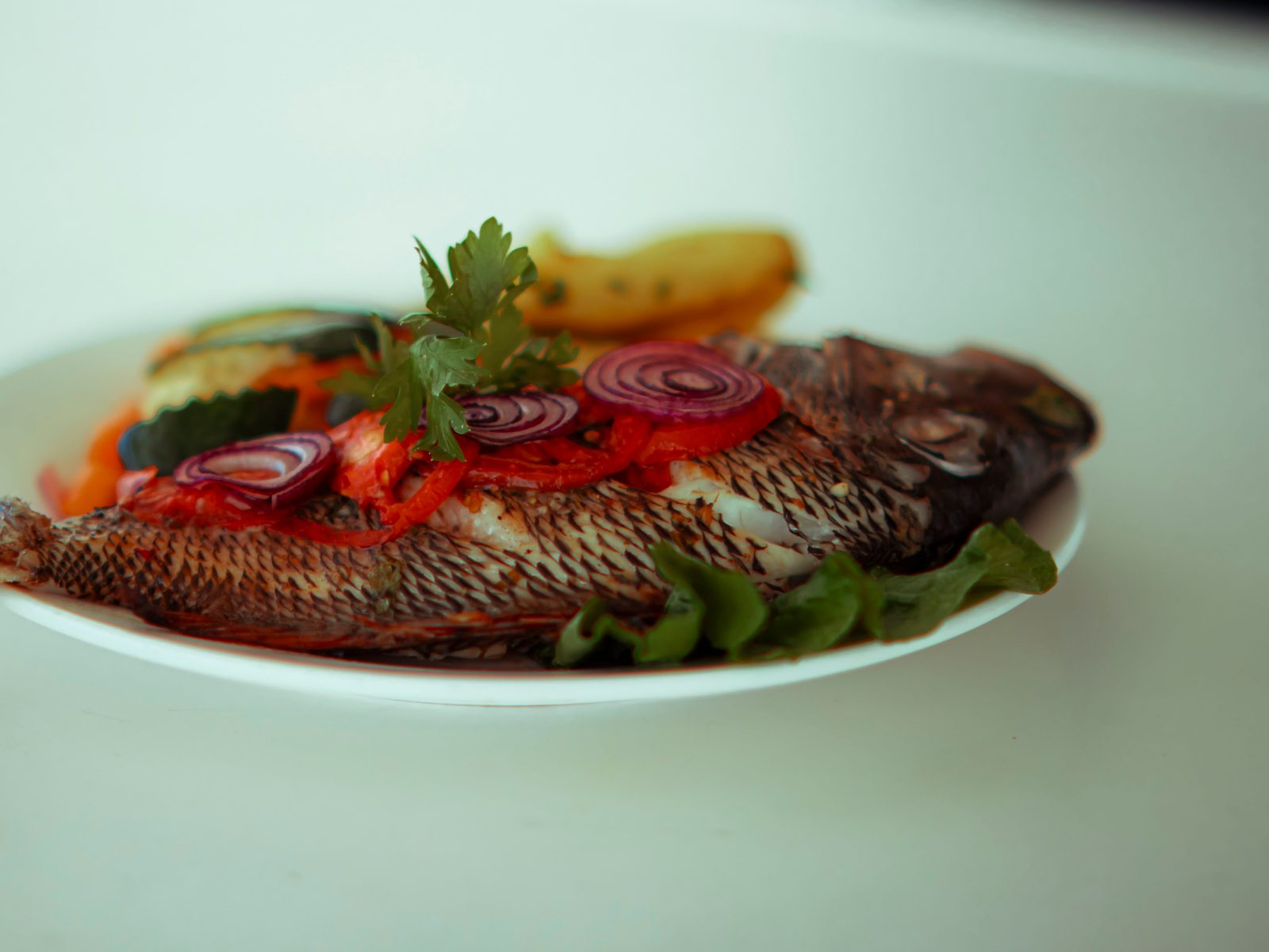 Whole grilled fish with fresh vegetables served on deck of a catamaran